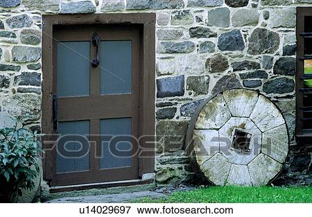 Stock Photo - Architectural exterior of stone wall, door and millstone. Fotosearch
