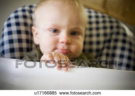 Stock Photography - Baby boy pouting in highchair. Fotosearch