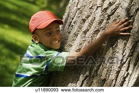 Boy hugging tree trunk View Large Photo Image Stock Image - Boy hugging tree trunk. Fotosearch