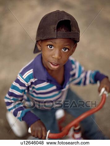 Boy riding a tricycle View Large Photo Image Stock Photo - Boy riding a tricycle. Fotosearch