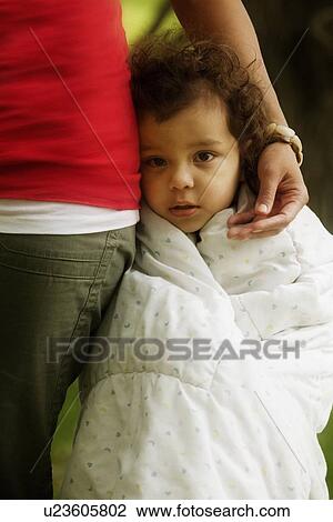 Stock Image - Child wrapped up in blanket at mother's side. Fotosearch
