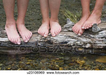 Stock Photo - Children standing on a log in a stream . Fotosearch