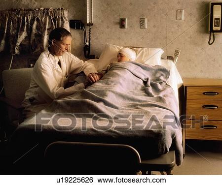 Stock Photograph - Doctor checking on a child in a hospital room. Fotosearch