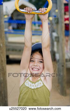 Stock Image - Girl hanging from playground ride . Fotosearch
