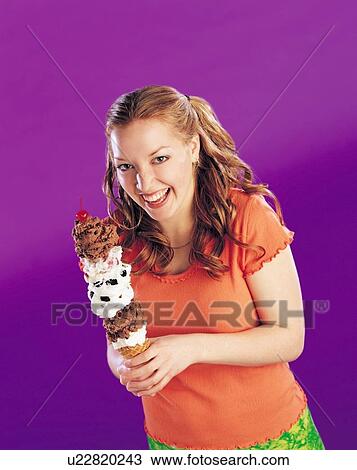 Stock Image - Girl holding a tall ice cream cone. Fotosearch