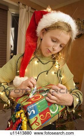 Stock Image - Girl peeking at a Christmas present. Fotosearch