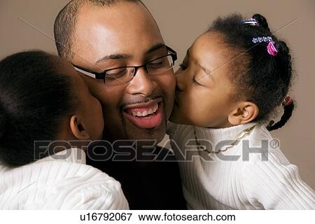Stock Photo - Girls kissing daddy on the cheek. Fotosearch