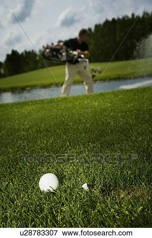 Golf ball and golfer in background View Large Photo Image Stock Photo - Golf ball and golfer in background. Fotosearch