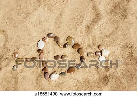 Heart pierced by cupid's arrow made out of stones and placed on sand View Large Photo Image Stock Photo - Heart pierced by cupid's arrow made out of stones and placed on sand. Fotosearch