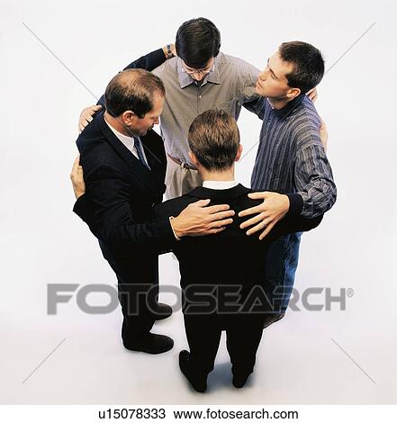 Stock Image - High angle view of men praying and standing in a circle. Fotosearch