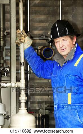 Stock Image - Industrial worker with oilfield equipment. Fotosearch