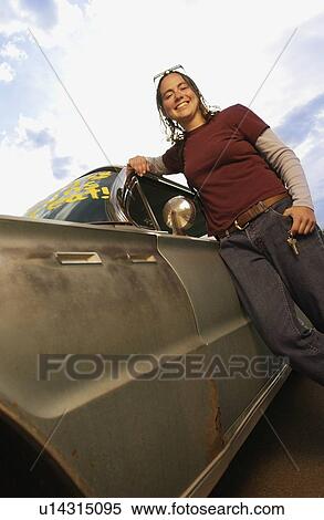Stock Photography - Low angle view of a girl posing by the car. Fotosearch