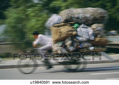 Stock Image - Man hauling a load of bags on a cycle rickshaw in Beijing, China. Fotosearch