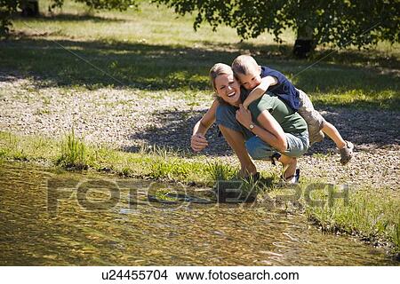 Mother giving son piggyback near lake View Large Photo Image Picture - Mother giving son piggyback near lake. Fotosearch