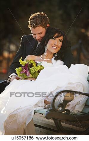 Stock Photograph - Newly married couple sitting on a bench. Fotosearch