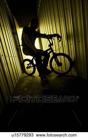 Stock Image - Person on a bike in a metal building. Fotosearch