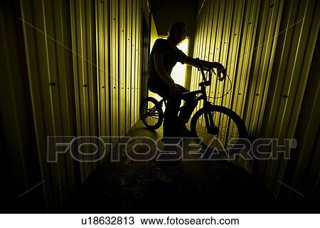Stock Image - Person on a bike in a metal building. Fotosearch