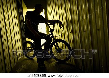 Stock Photography - Person on a bike in a metal building. Fotosearch