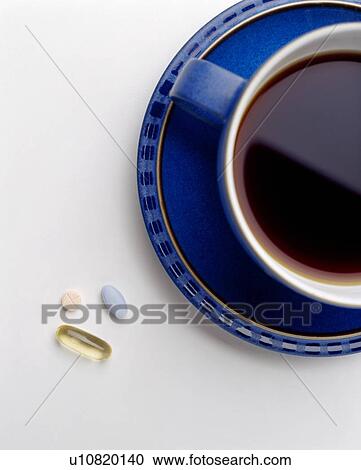 Stock Image - Pills beside a cup of coffee. Fotosearch