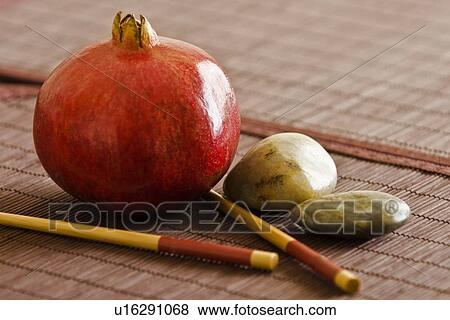 Stock Photo - Pomegranate with chopsticks and pebbles. Fotosearch