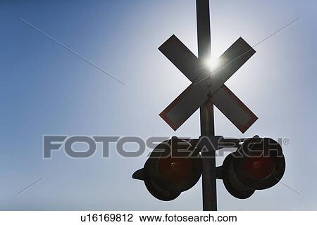 Stock Image - Railroad crossing lights with sun glare. Fotosearch