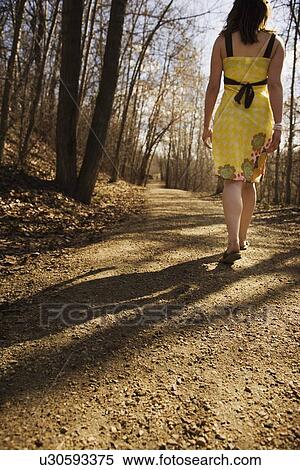 Rear view of woman walking on gravel pathway View Large Photo Image Stock Photography - Rear view of woman walking on gravel pathway. Fotosearch