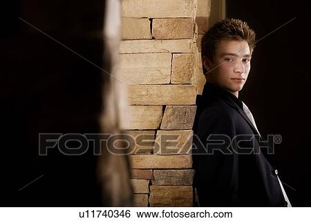 Stock Photograph - Side view of a man standing by wall. Fotosearch