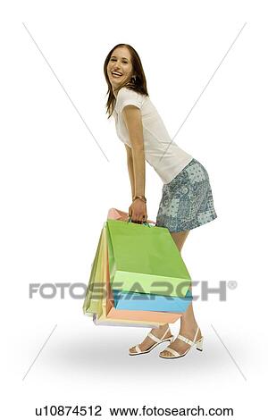 Side view of a woman smiling and holding shopping bags View Large Photo Image Stock Image - Side view of a woman smiling and holding shopping bags. Fotosearch