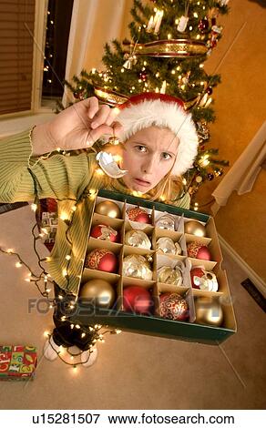 Stock Photo - Teenage girl tangled in christmas lights holding decorations. Fotosearch