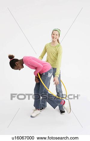 Two girls playing with hula hoop View Large Photo Image Stock Image - Two girls playing with hula hoop. Fotosearch