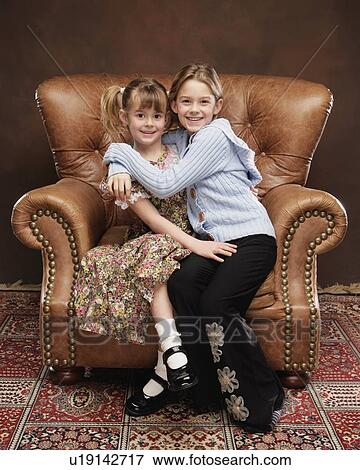 Two girls sitting in armchair View Large Photo Image Stock Photo - Two girls sitting in armchair. Fotosearch