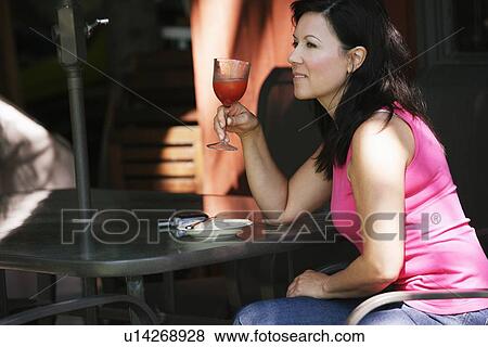 Stock Photo - Woman drinking on patio. Fotosearch