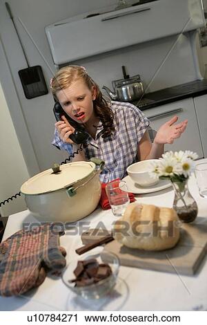 Stock Image - Woman in a 1940's style kitchen. Fotosearch