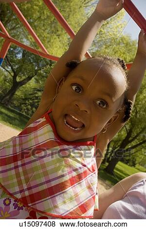 Young girl hanging from playground equipment View Large Photo Image Stock Photo - Young girl hanging from playground equipment. Fotosearch