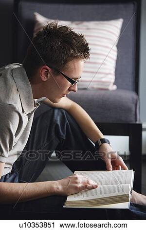 Young man sitting on floor reading a book View Large Photo Image Stock Image - Young man sitting on floor reading a book. Fotosearch