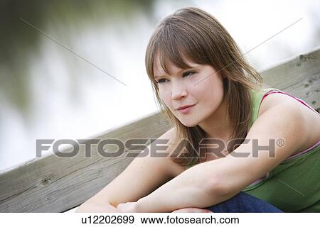 Young woman sitting, looking away View Large Photo Image Stock Photo - Young woman sitting, looking away. Fotosearch