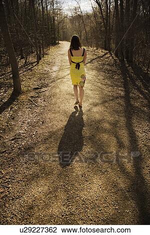 Stock Image - Young woman walking on a path. Fotosearch