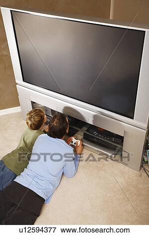 Stock Photo - Father and son using TV game controllers. Fotosearch