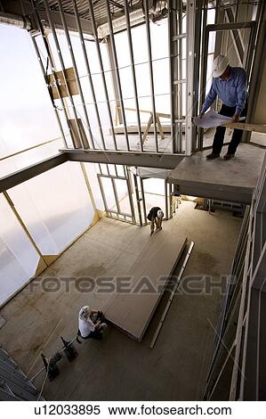 Foreman and drywallers at a construction site View Large Photo Image Stock Photography - Foreman and drywallers at a construction site. Fotosearch