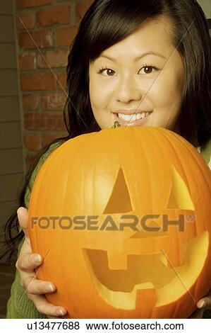 Girl holding a jack-o-lantern View Large Photo Image Stock Photo - Girl holding a jack-o-lantern. Fotosearch