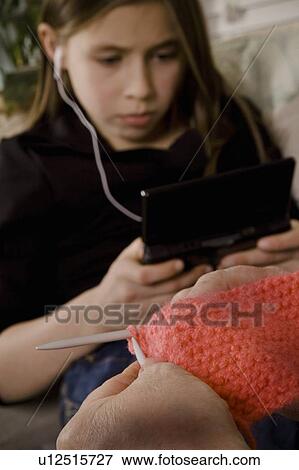 Girl with earbuds in and another person knitting View Large Photo Image Stock Photo - Girl with earbuds in and another person knitting. Fotosearch