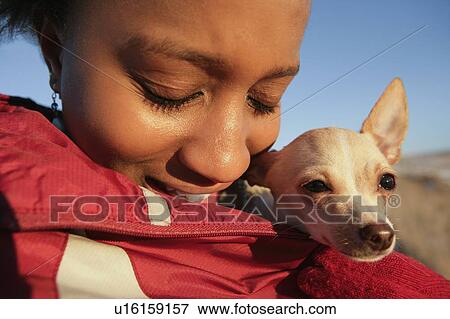 Stock Photo - Girl with small dog wrapped in her coat. Fotosearch