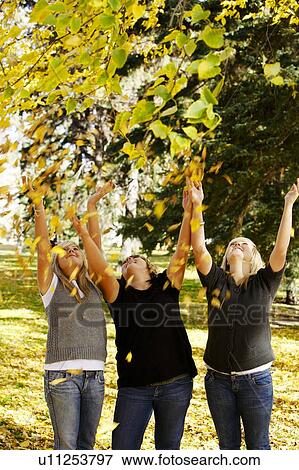 Girls throwing leaves in the air View Large Photo Image Stock Photo - Girls throwing leaves in the air. Fotosearch