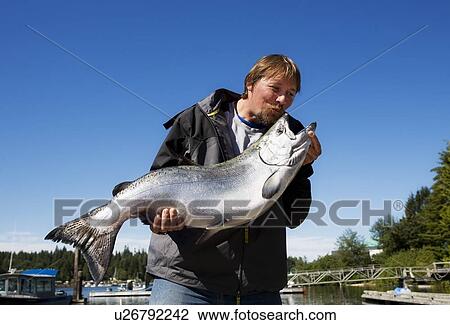 Stock Image - Man kissing his fish. Fotosearch