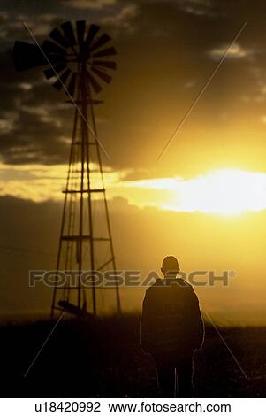 Stock Image - Man standing by a windmill. Fotosearch