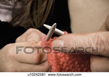 Stock Image - Person helping another learn to knit. Fotosearch