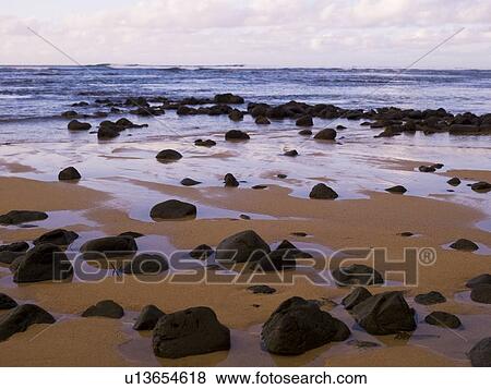Stock Photo - Rocks scattered on the beach, Hanalei Bay, Kauai, Hawaii. Fotosearch