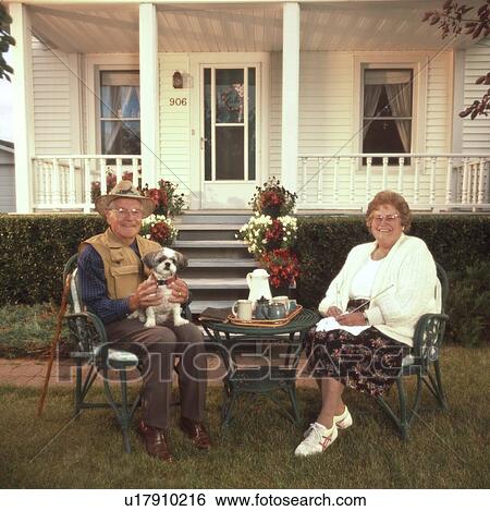 Stock Photograph - Senior couple relaxing in front of house. Fotosearch