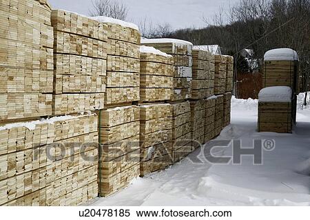 Stock Photography - Softwood lumber in piles at winter. Fotosearch