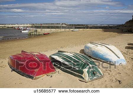 Stock Photo - Three overturned boats on the beach, North Yorkshire, United Kingdom. Fotosearch